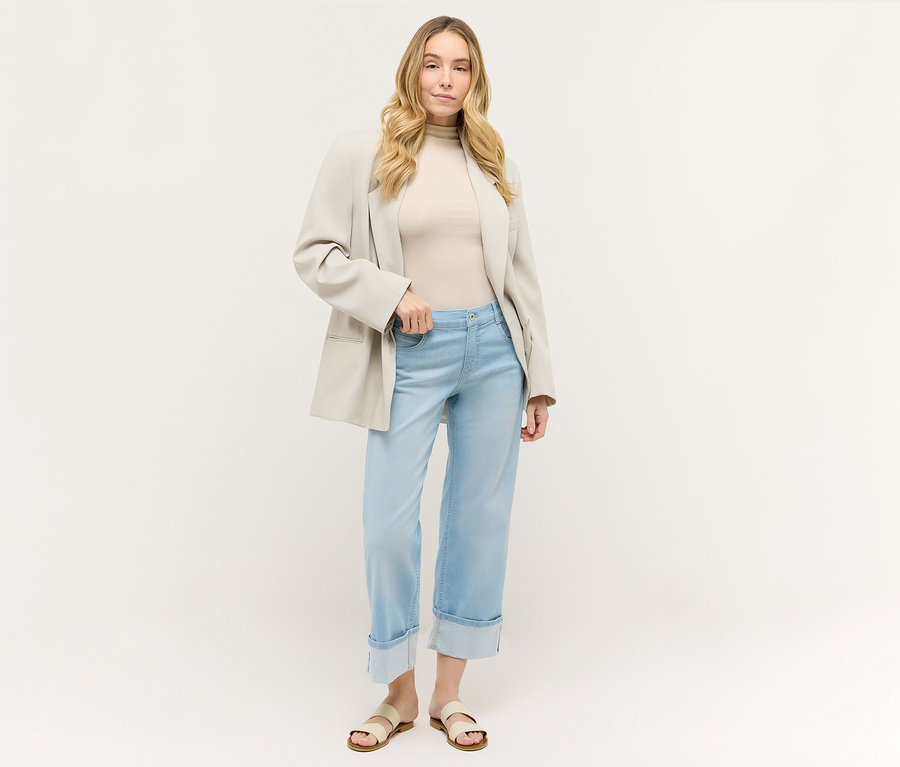 Femme portant un jean Angels Denim « Laia Turn-Up » Wide Leg bleu clair avec un haut beige et un blazer.