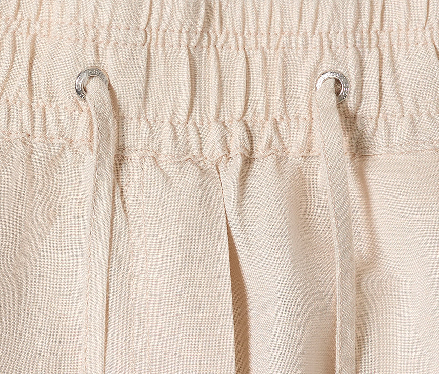 Gros plan d'un pantalon beige avec cordon de serrage et cordon.