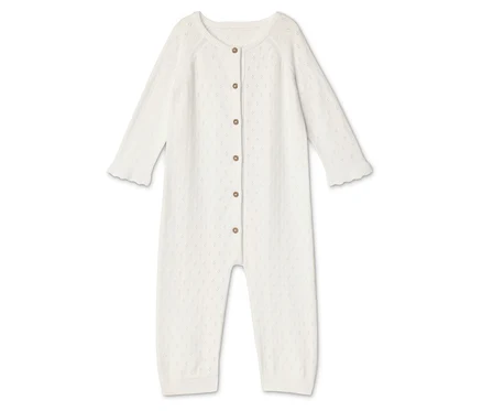 Une grenouillère blanche pour bébé avec des boutons est posée sur un fond blanc.