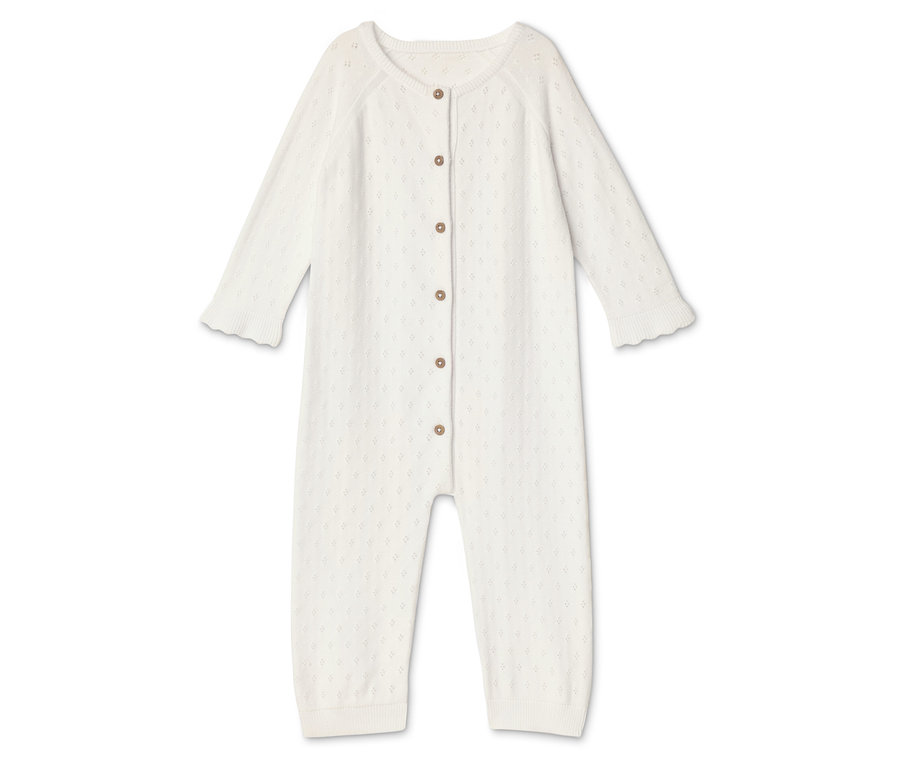 Une grenouillère blanche pour bébé avec des boutons est posée sur un fond blanc.