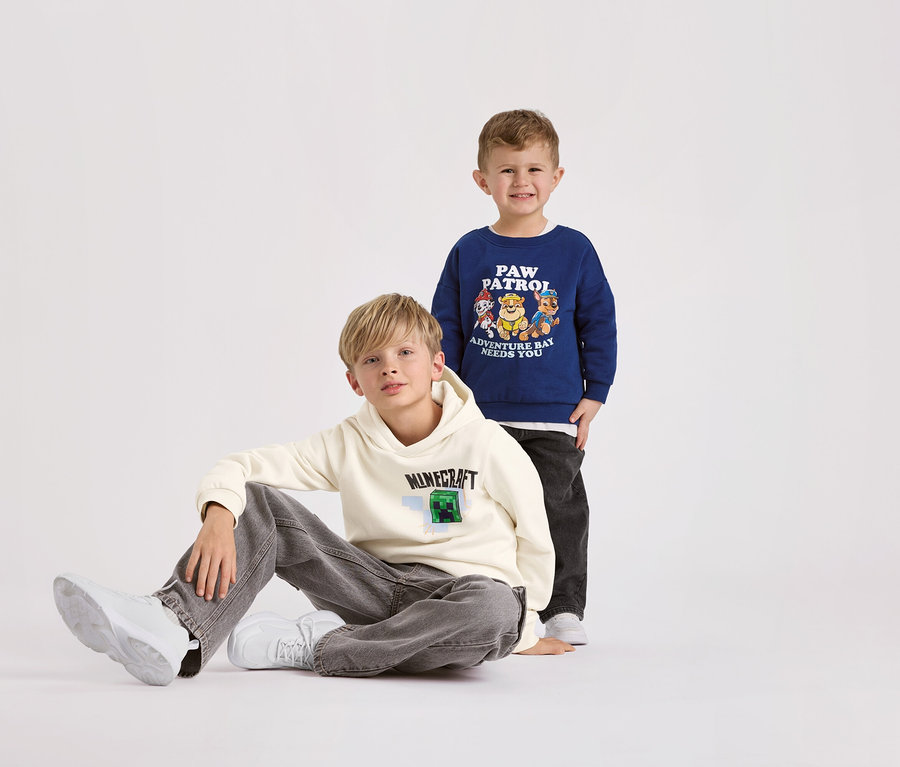 Deux garçons posent sur un fond blanc. Le garçon au premier plan porte un sweat-shirt MINECRAFT pour enfant avec intérieur gratté.