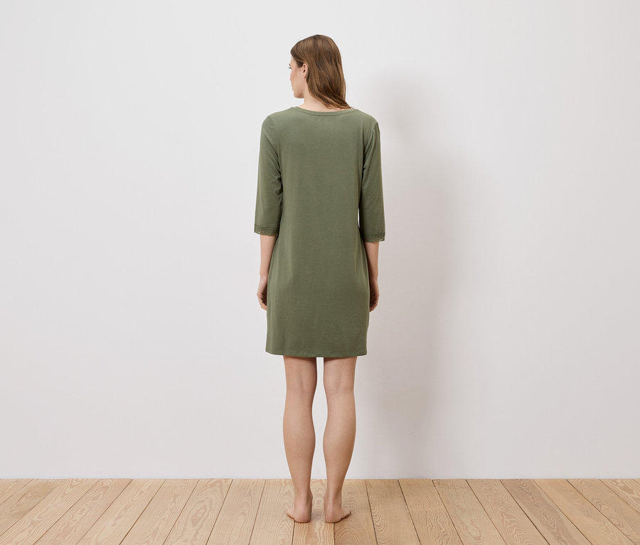 Une femme se tient dos à la caméra et porte une robe vert olive à manches trois quarts.