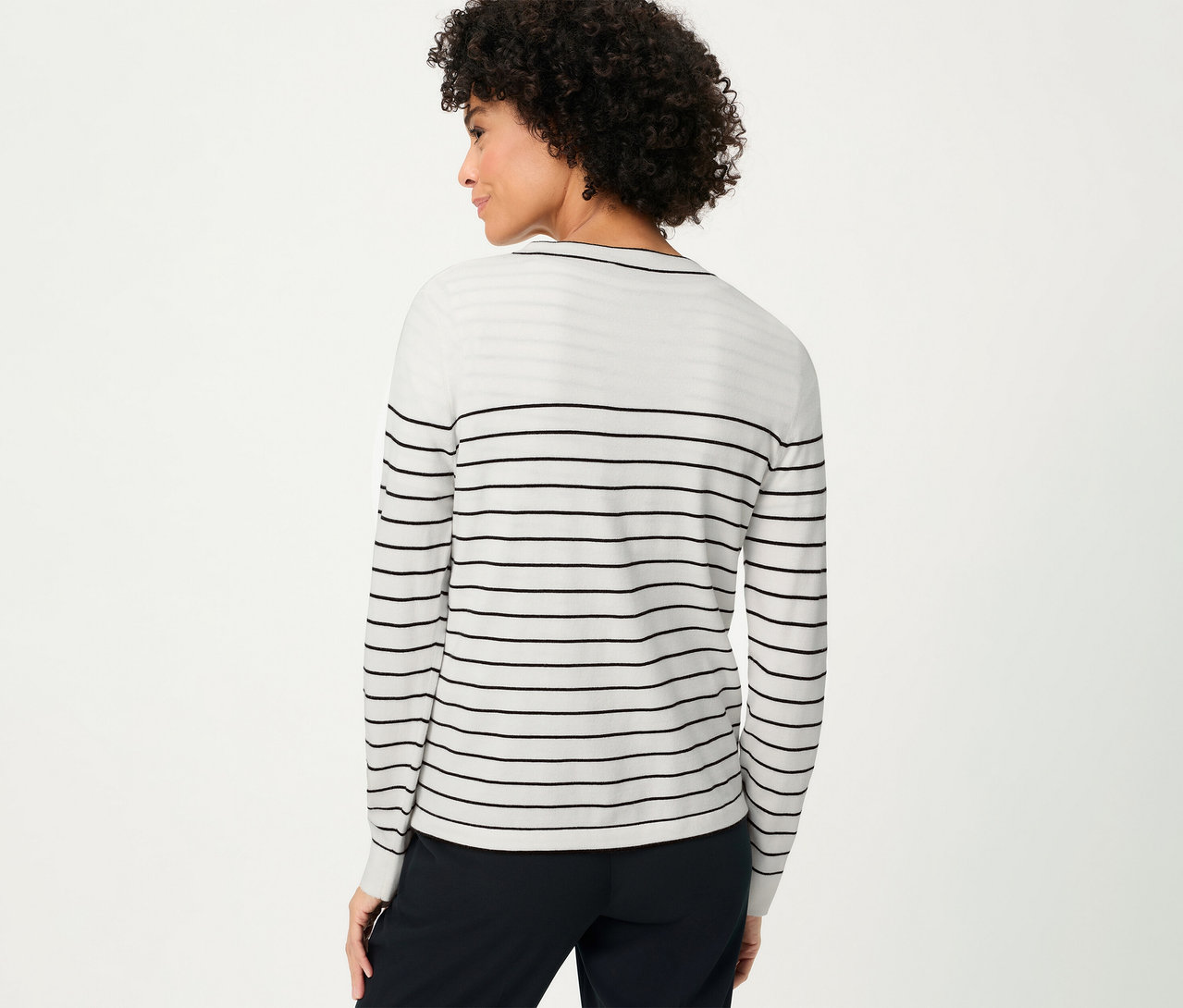 Femme vue de dos portant un cardigan Olsen «
LA
» blanc à rayures noires et un pantalon foncé.