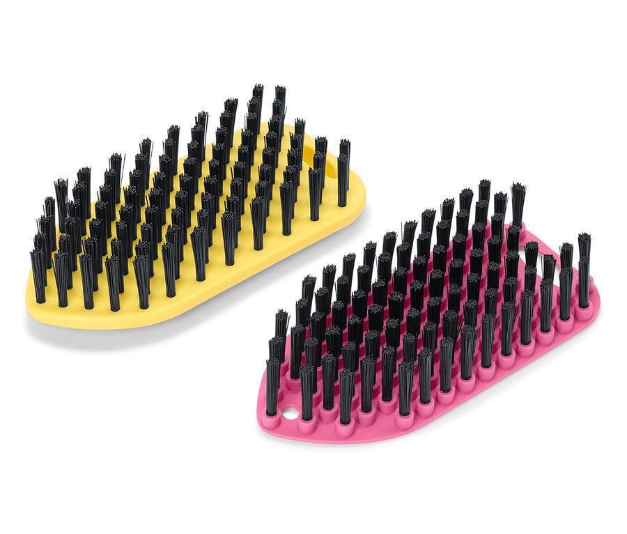 Deux brosses sont posées sur un fond blanc, une jaune et une rose, toutes deux avec des poils noirs.