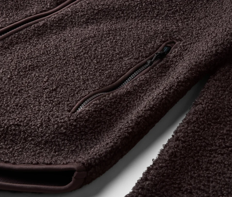 Gros plan d'une veste polaire marron avec fermeture éclair et poche zippée.