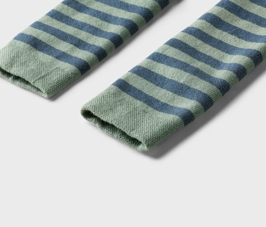 Gros plan de deux chaussettes rayées vertes et bleues sur fond blanc.