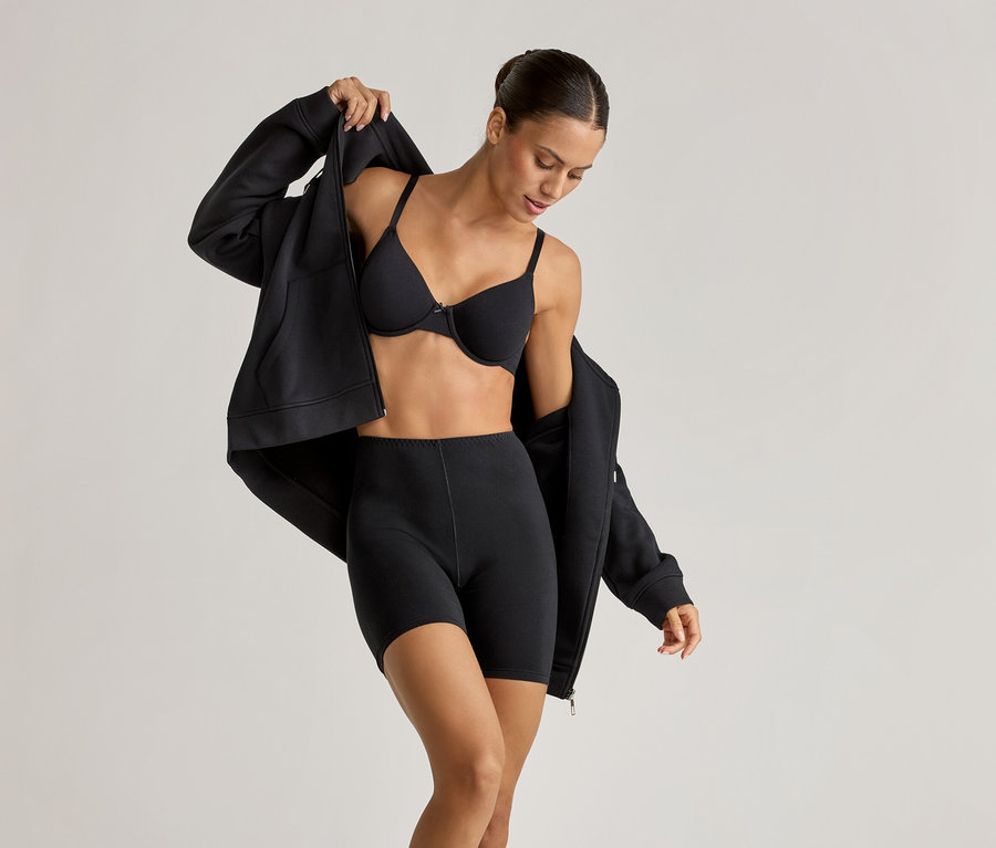 Femme portant un soutien-gorge à armatures noir, 2 cyclistes et une veste d’intérieur qu'elle ouvre.