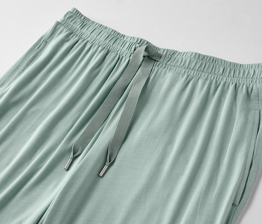 Gros plan d'un pantalon vert clair avec cordon de serrage et poches.