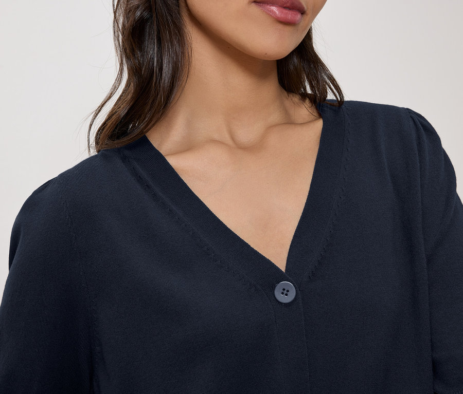 Gros plan d'une femme portant un cardigan en tricot bleu marine avec un col en V et un bouton.