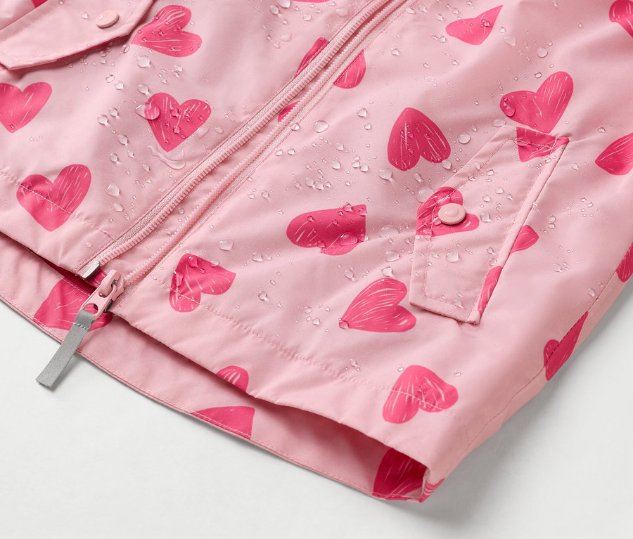 Gros plan d'un imperméable rose à motif de cœurs avec des gouttes d'eau.