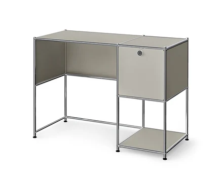 Un bureau modulaire gris clair avec un cadre chromé, comprenant un espace de travail à gauche et une unité de rangement à droite avec un placard fermé et une étagère ouverte.