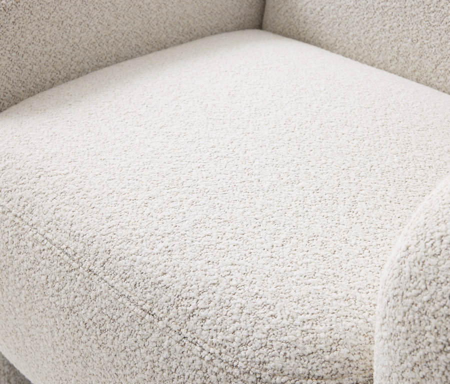 Gros plan d'un tissu bouclé texturé de couleur beige clair, montrant l'assise et l'accoudoir d'un meuble.