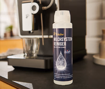 Le Nettoyant durgol® pour système à lait	, 250 ml est placé à côté d'une machine à café.