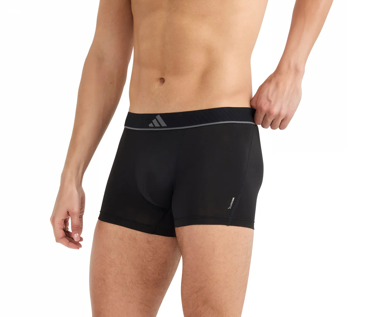 Homme portant un boxer noir à taille grise, tirant sur la taille avec sa main droite.