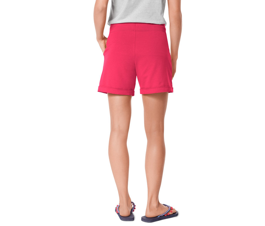 Femme vue de dos portant un short rose et des tongs.