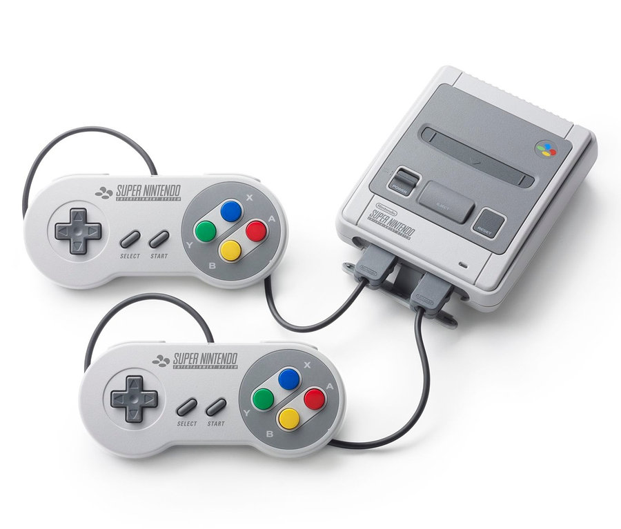Deux contrôleurs gris et une console de jeux Nintendo Classic Mini : Super Nintendo Entertainment System sur fond blanc.