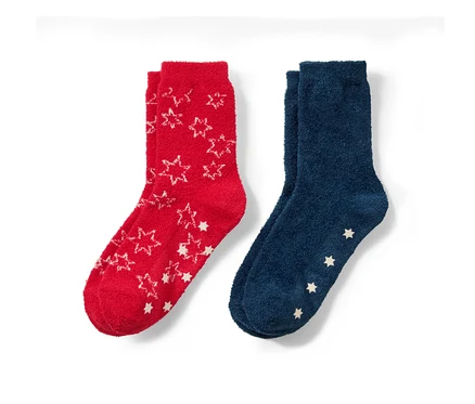 Deux paires de chaussettes moelleuses pour enfant : une paire rouge avec des étoiles blanches et une paire bleue avec des étoiles blanches sur les pieds.