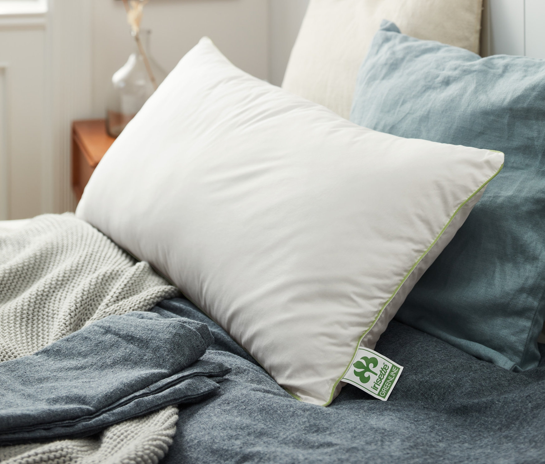 Plusieurs oreillers irisette® greenline de différentes tailles sont posés sur un lit.