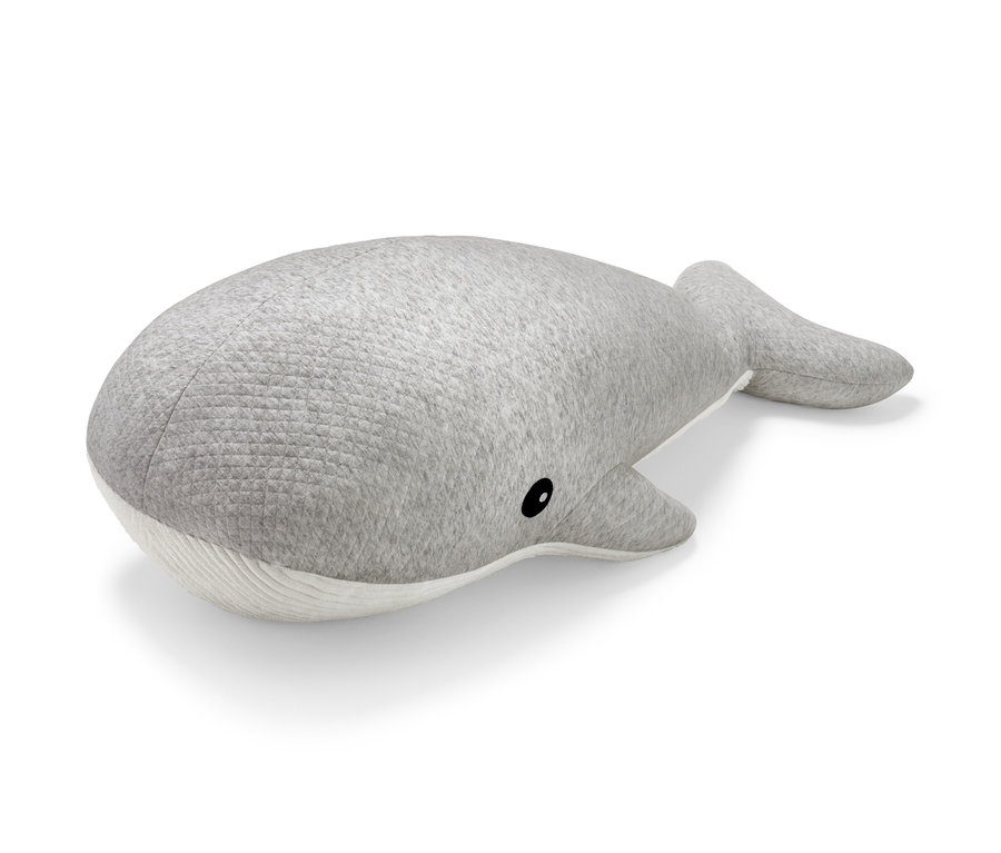 Une baleine géante en peluche grise est allongée sur un fond blanc.