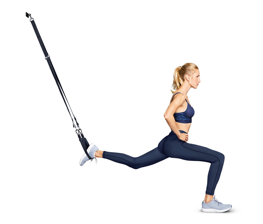 Femme faisant des fentes à l'aide de sangles de suspension.