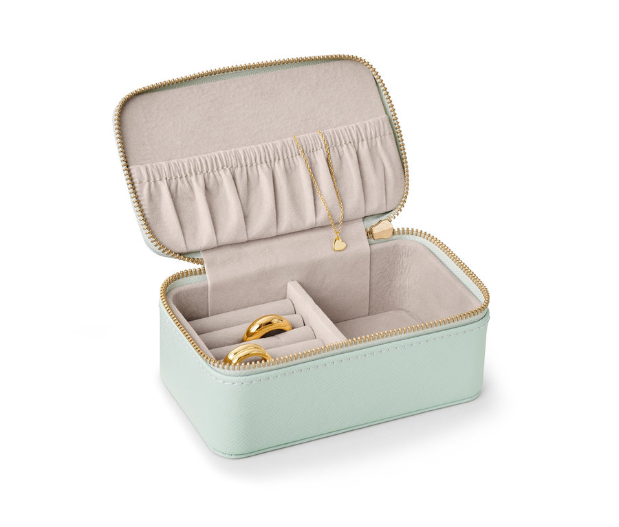 Petite boîte à bijoux ouverte vert clair avec des bagues en or et un collier.