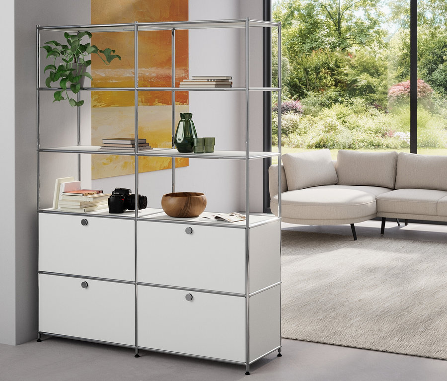 Un salon présente une étagère en métal «
CN3
» à 2 compartiments et une étagère haute en métal «
CN3
» à 4 abattants, blanc. Sont également présentés un jeu d'abattants supplémentaires en métal «
CN3
», orange et un jeu de parois de fond supplémentaires en métal «
CN3
», jaune.