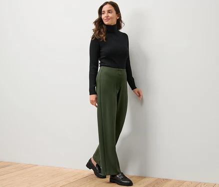 Femme portant un pull à col roulé noir et un pantalon en jersey.