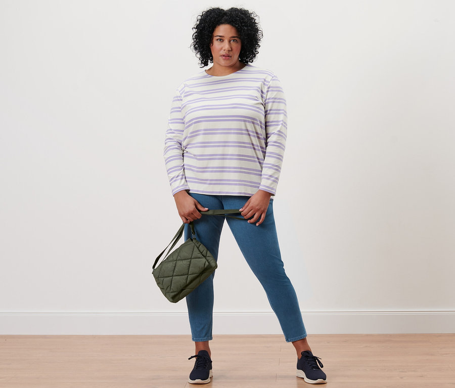 Femme posant en jegging, chemise à manches longues rayée lilas-crème et sac matelassé à bandoulière.
