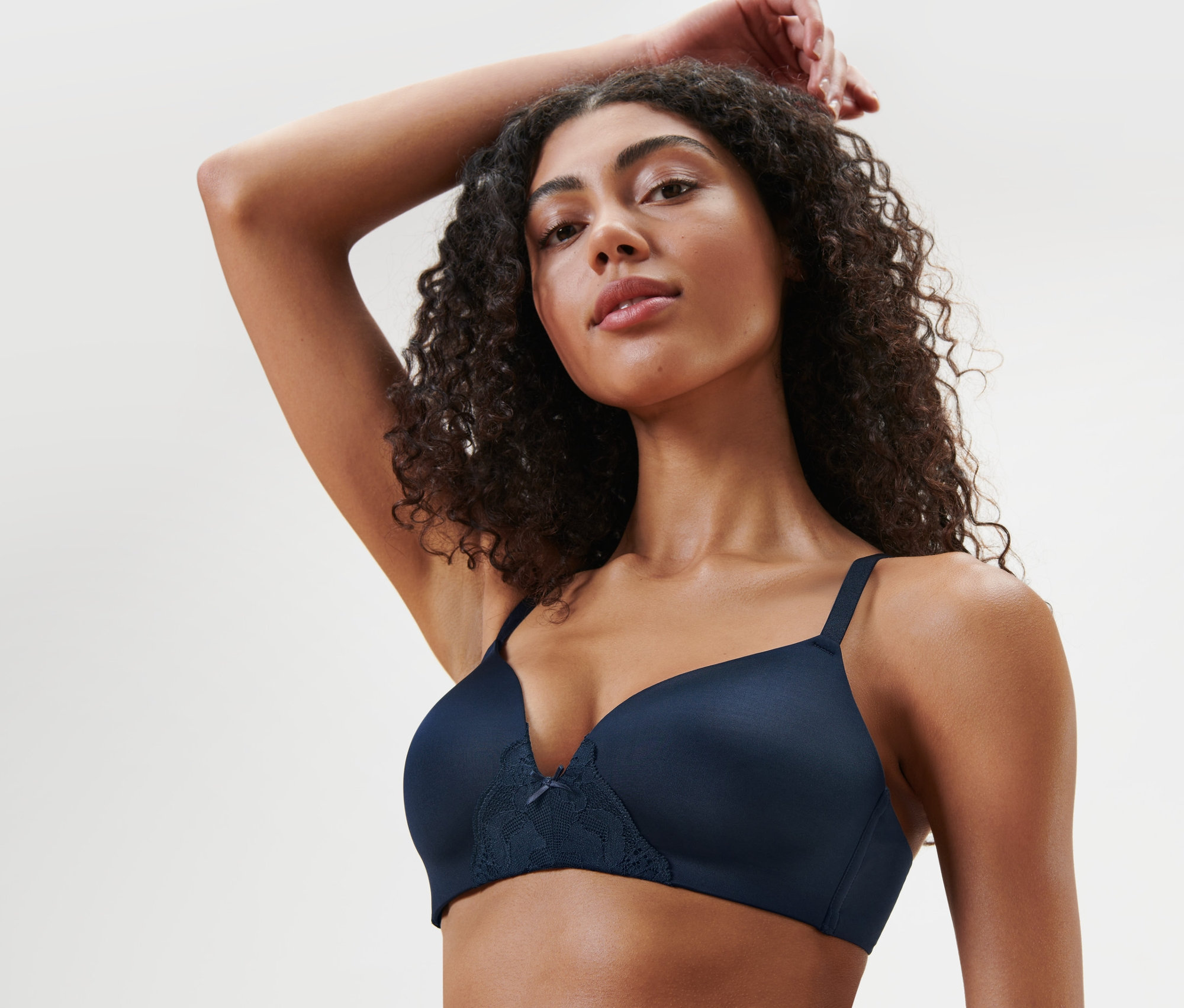 Une femme, une main au-dessus de la tête, porte un soutien-gorge bleu à coques souples.