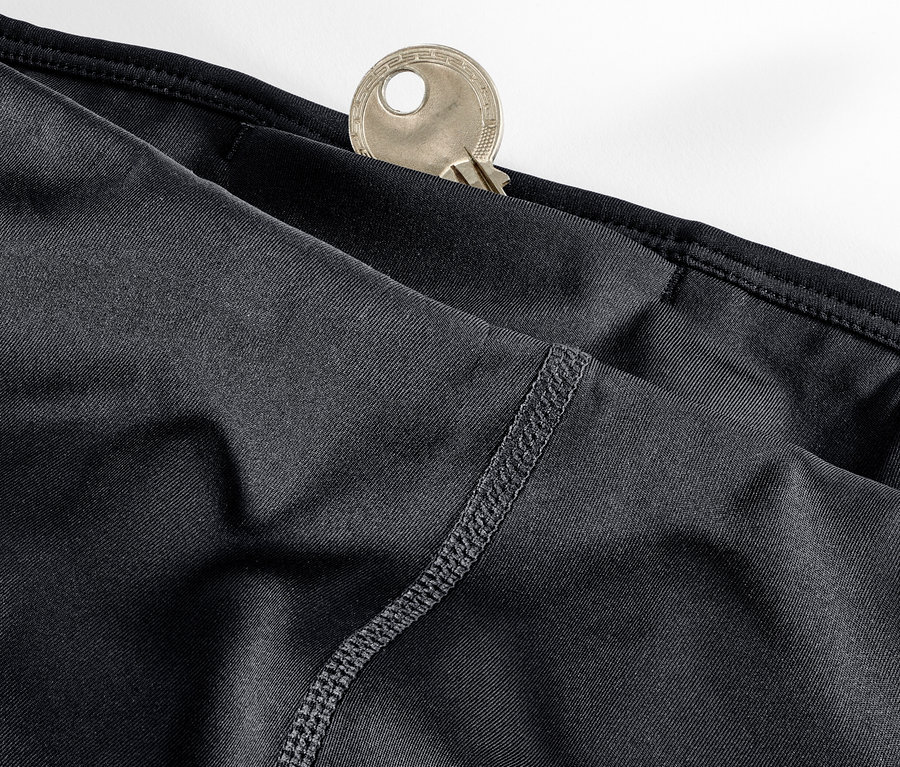 Gros plan sur un legging de sport 3/4 noir avec une clé dans la poche.