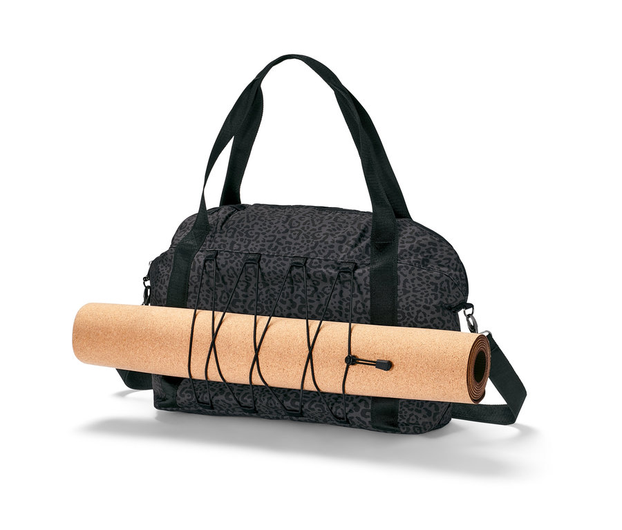 Un sac de sport gris avec imprimé intégral et un tapis d'entraînement enroulé.