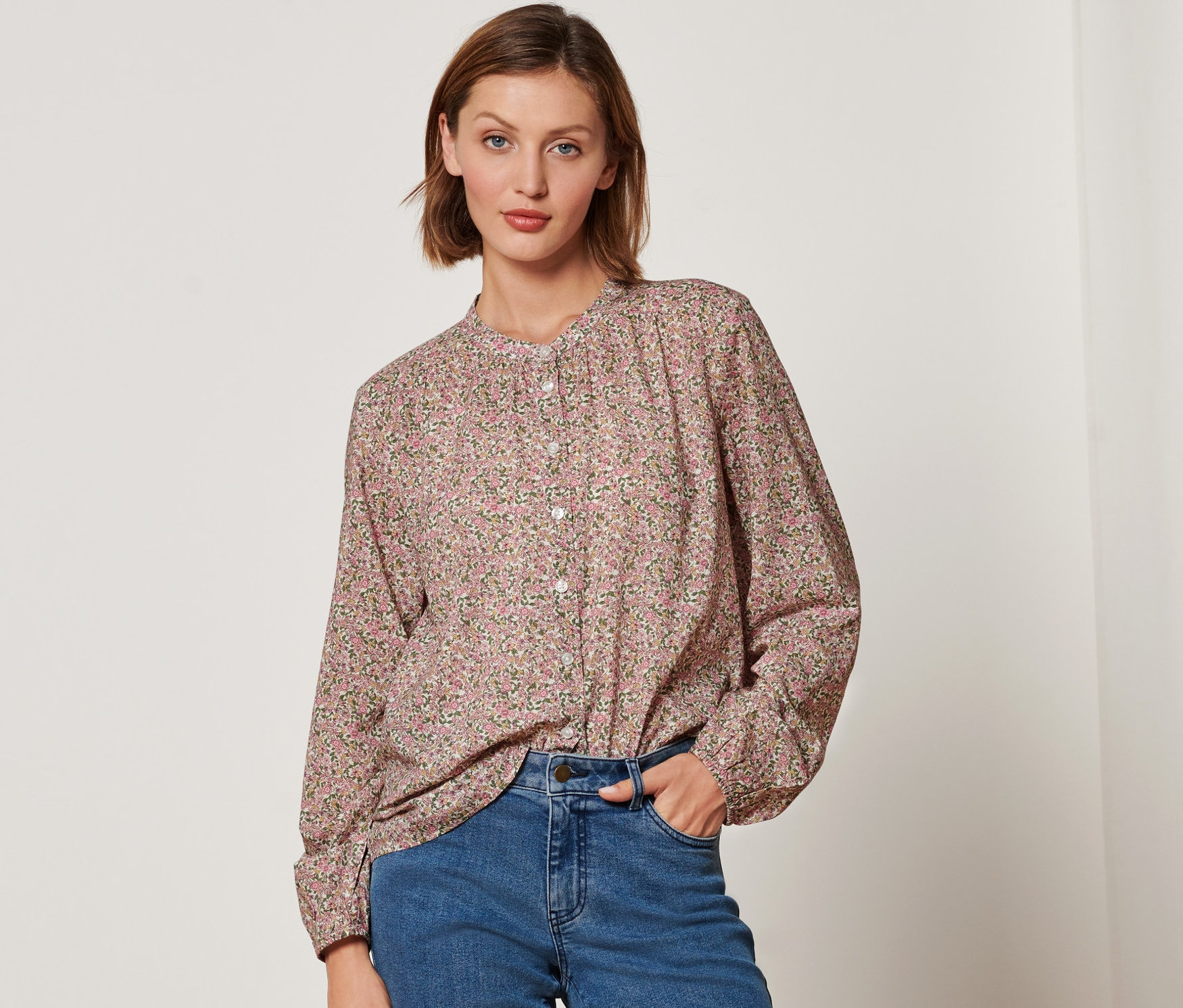 Femme portant un chemisier à fleurs et un jean.