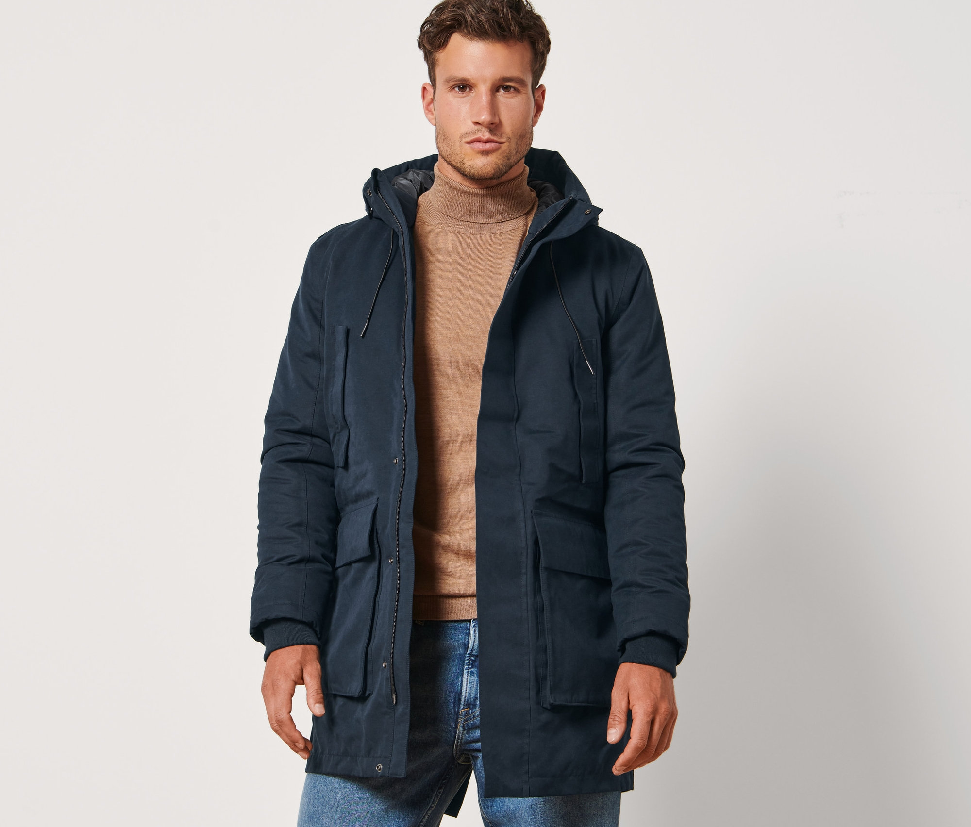 Un homme debout portant une parka bleu marine.