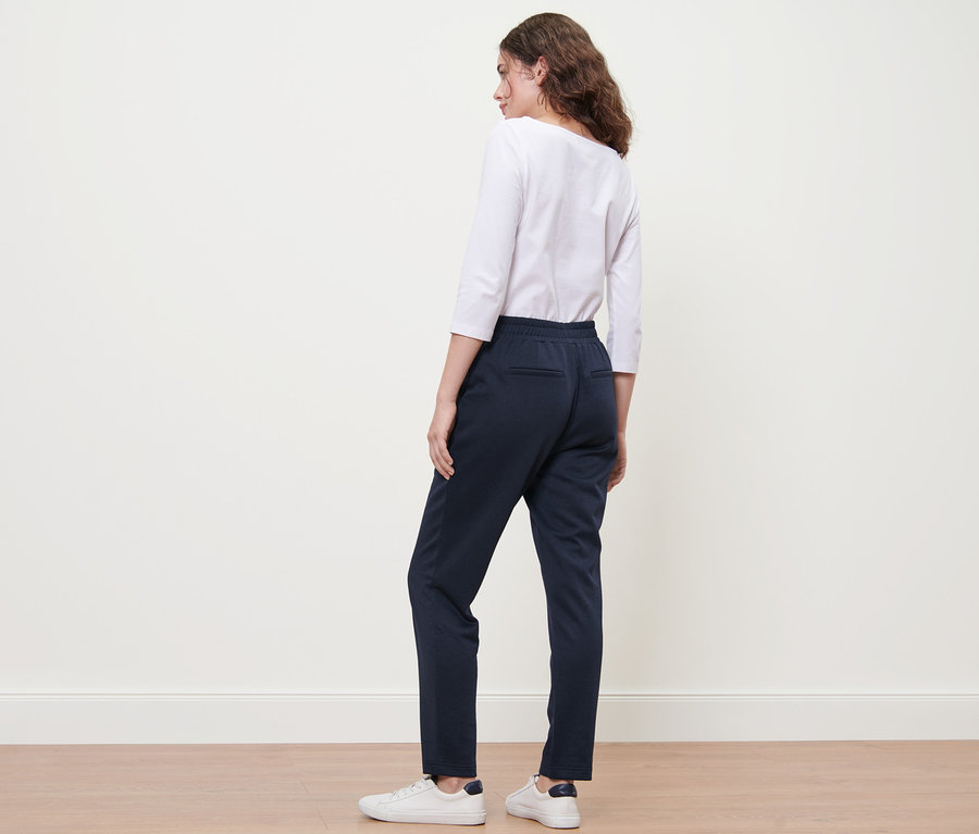 Femme debout de dos portant un jogpant bleu foncé.