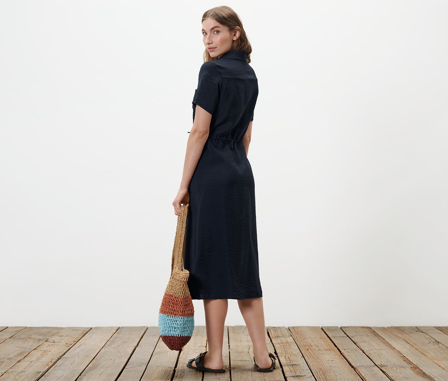 Femme regardant par-dessus son épaule et portant une robe-chemisier.
