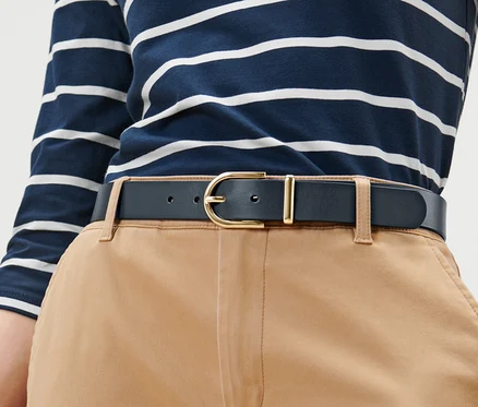 Femme portant une ceinture en cuir avec une boucle en métal.
