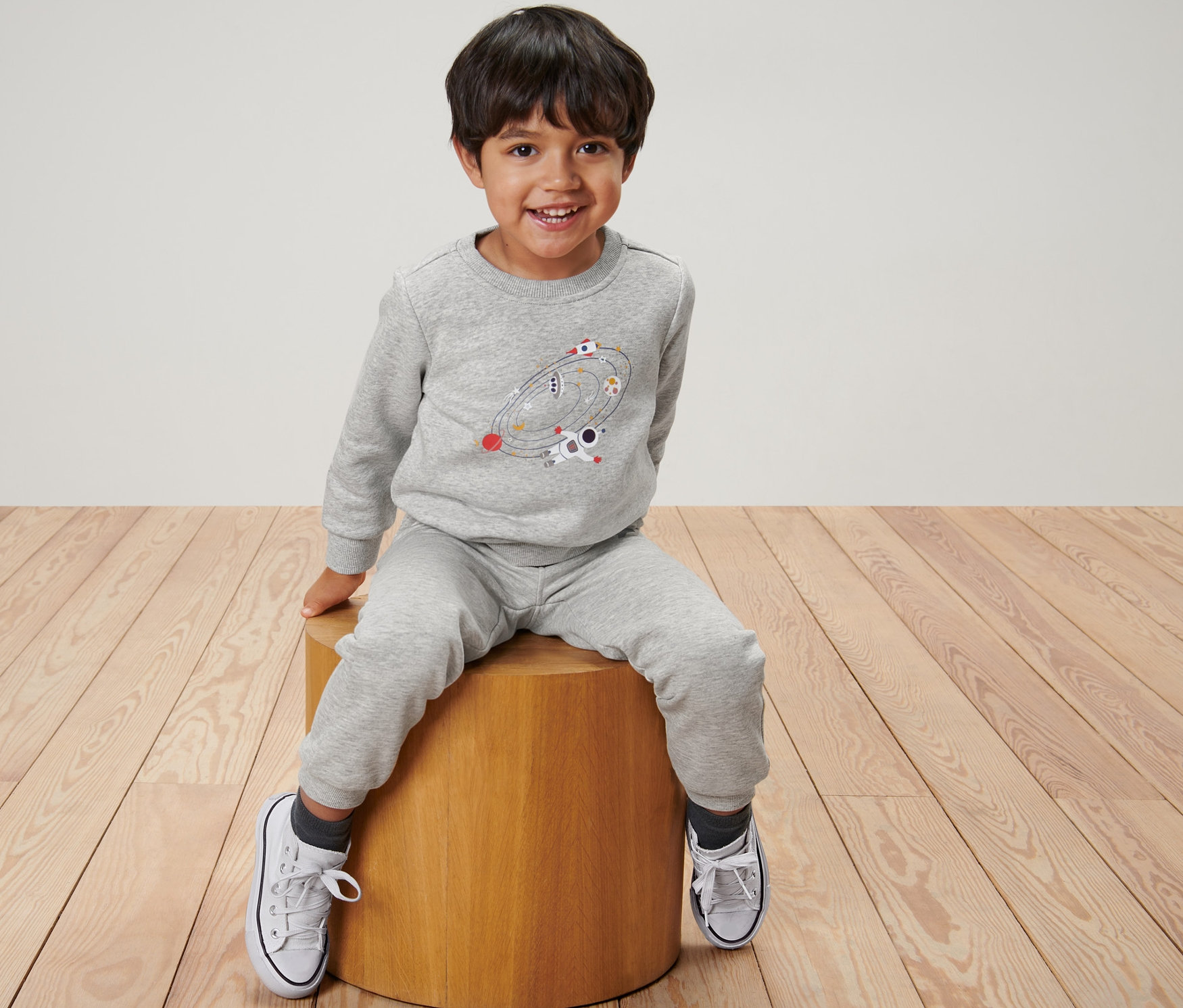 Un garçon est assis sur un tabouret et porte un sweater pour enfant, espace.