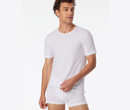 Un homme porte 2 t-shirts blancs SCHIESSER en coton bio.