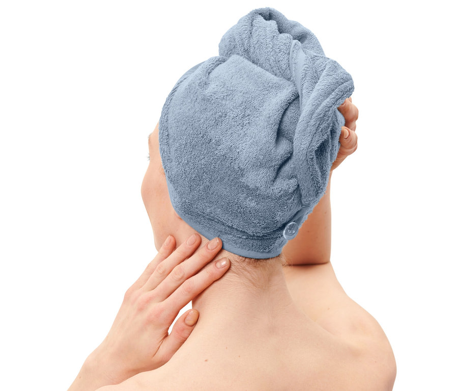 Femme avec une serviette turban bleu clair sur la tête et une serviette de la même couleur enroulée autour du corps.