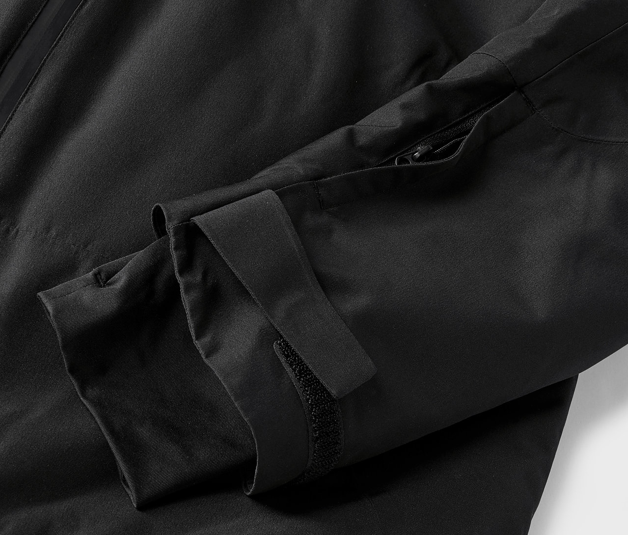 Gros plan sur une veste noire avec une manche et une fermeture éclair.