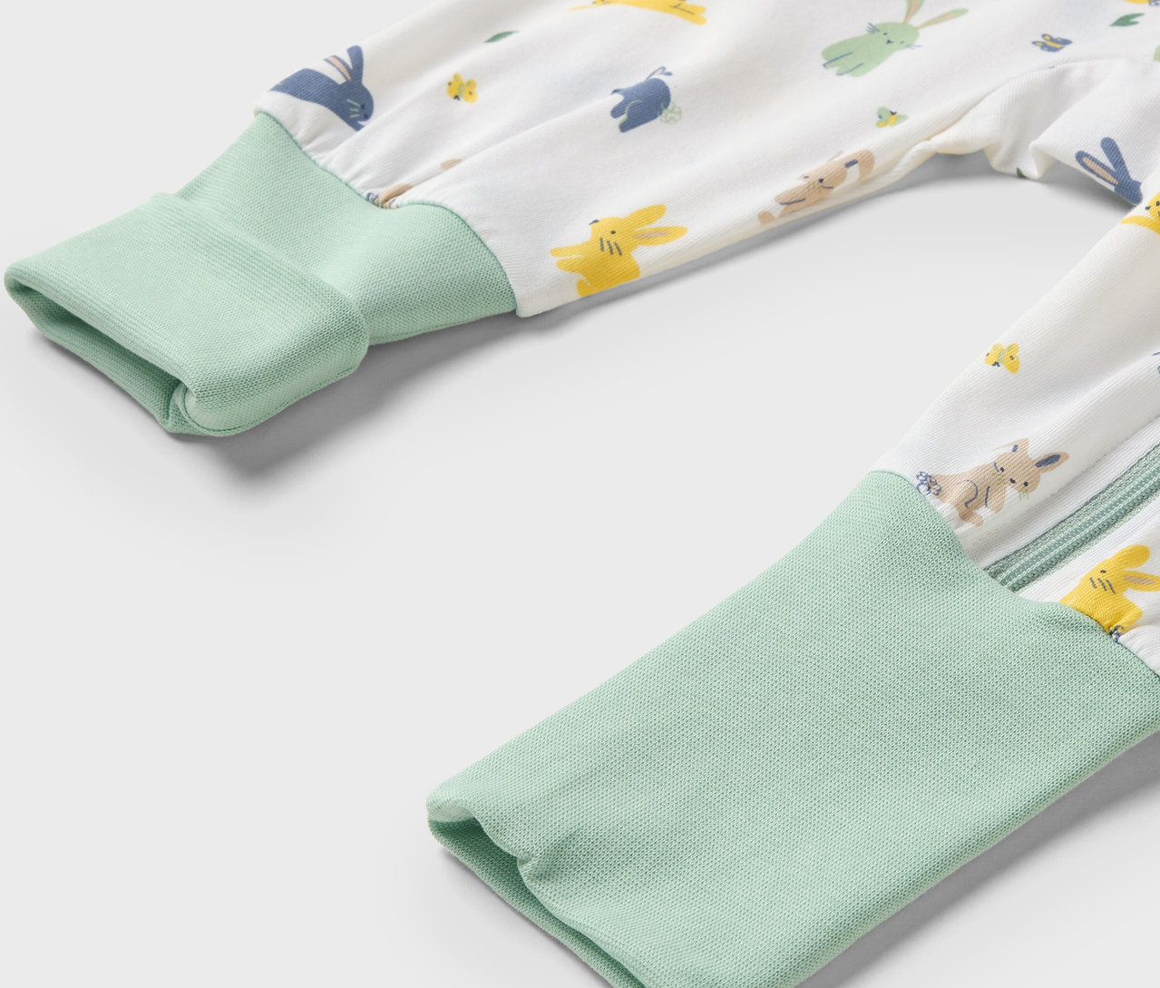 Gros plan sur un pyjama pour bébé avec un motif de lapins et des bordures vert clair aux manches.