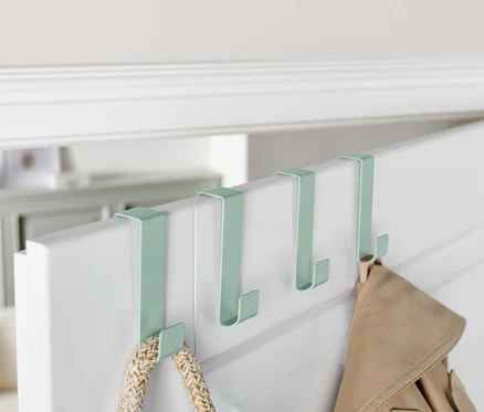 Quatre crochets de porte verts sont suspendus au bord supérieur d'une porte blanche.