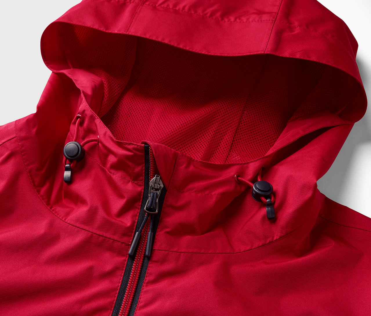 Vue détaillée d'une veste de pluie rouge avec fermeture éclair et capuche.