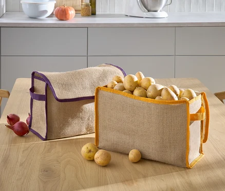 Deux paniers beiges sont posés sur une table, l'un avec un bord violet est vide et l'autre avec un bord orange est rempli de pommes de terre.