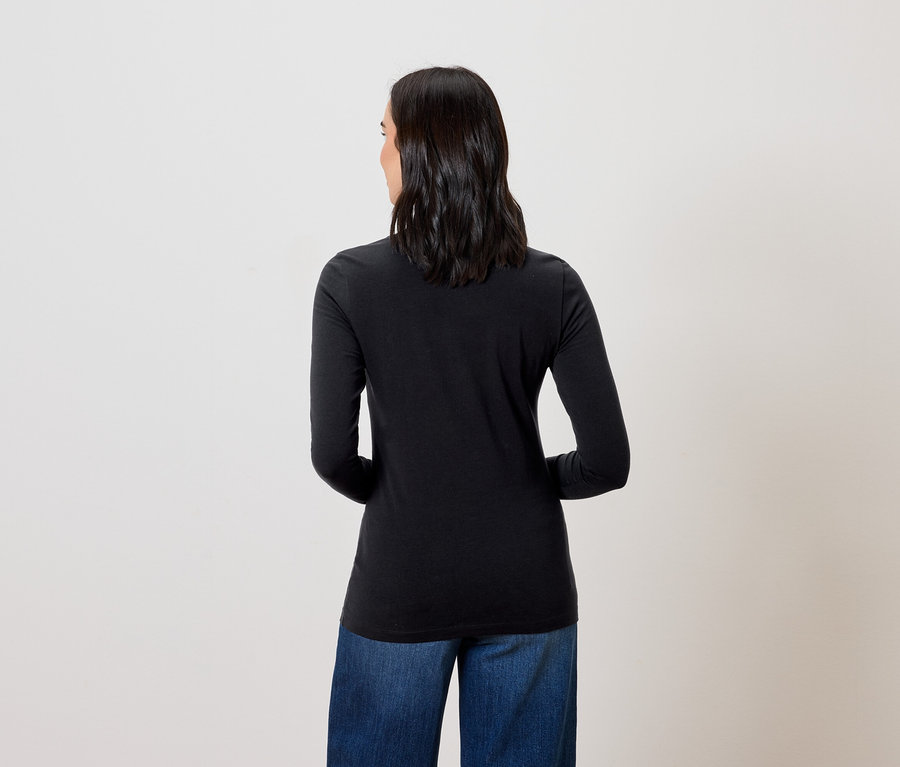 Une femme, de dos, porte un t-shirt noir à manches longues et un jean bleu.