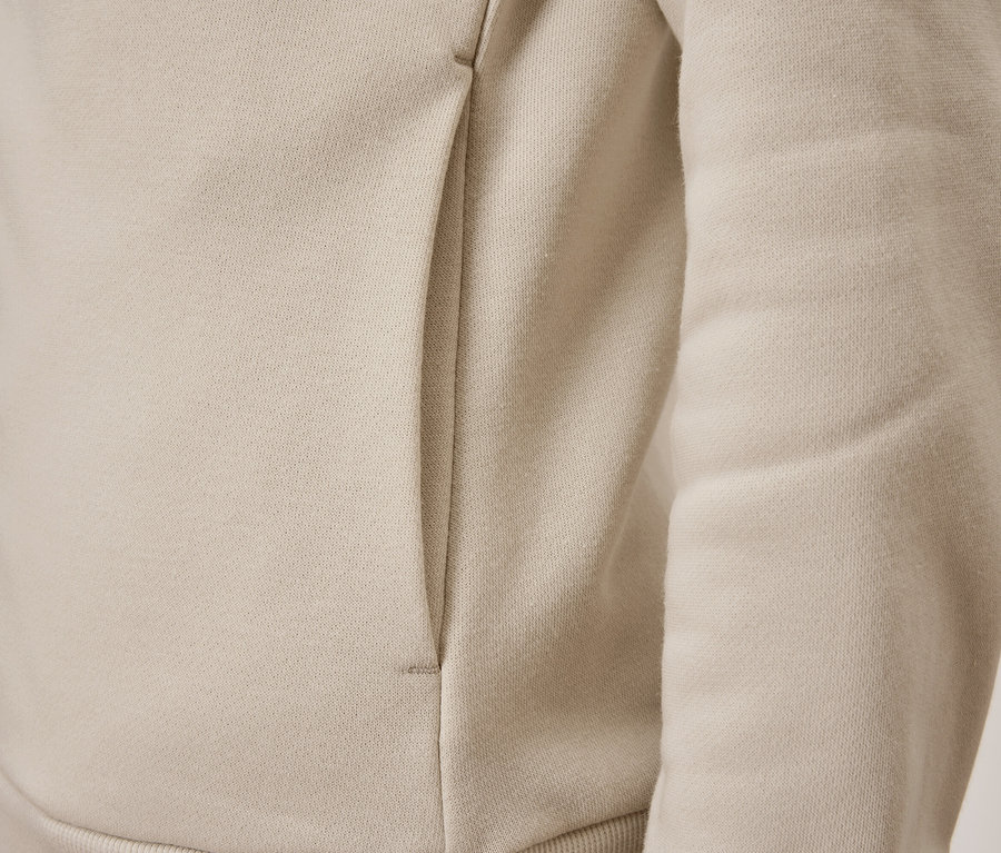 Gros plan sur un sweat-shirt beige avec une poche.