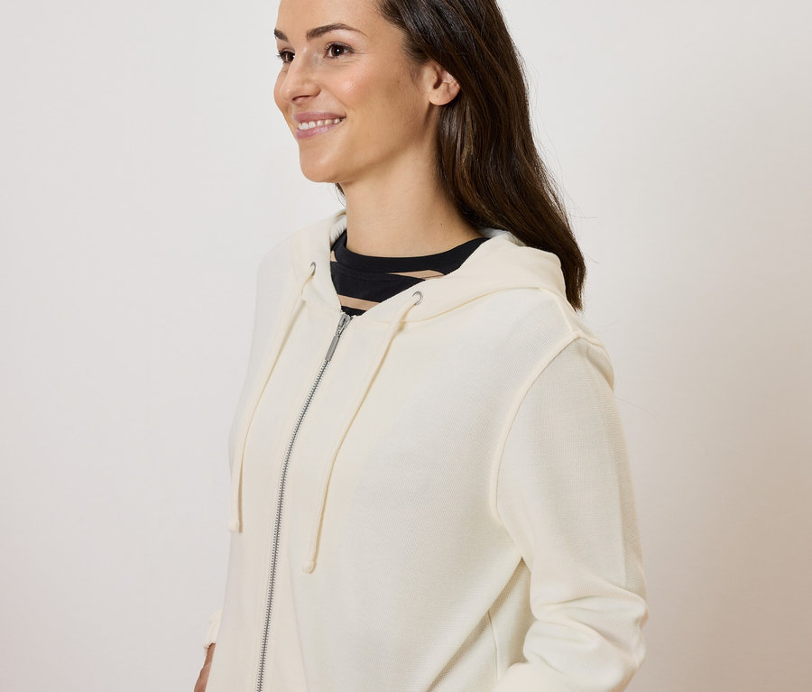 Femme posant dans un sweat à fermeture éclair crème.
