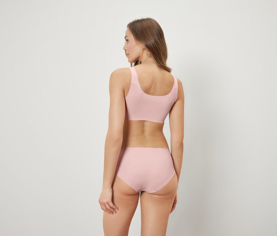Une femme vue de dos porte un soutien-gorge et une culotte roses.