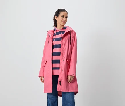 Une femme porte un manteau rose et un sweat à capuche rayé.