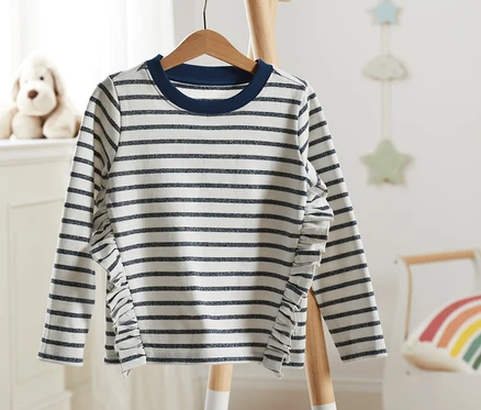Un sweat-shirt rayé avec des détails scintillants est suspendu à un cintre en bois.